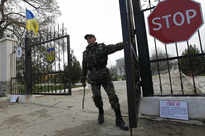 Ukrajinský voják zavírá bránu na letecké základně Belbek na Krymu