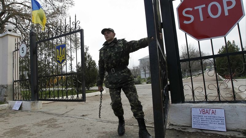 Ukrajinský voják zavírá bránu na letecké základně Belbek na Krymu