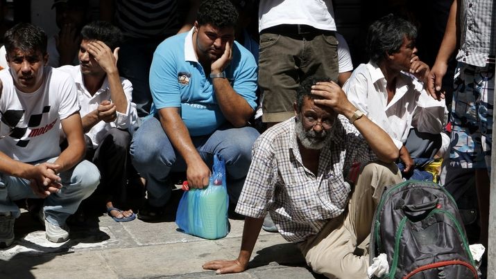 Ilegální imigranti čekají na transport na aténskou policejní stanici. 