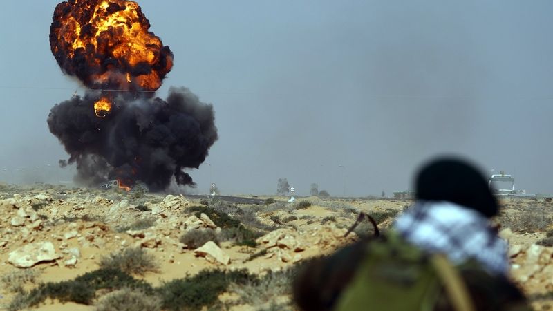 Libyjský vzbouřenec sleduje zásah do vozidla mezi městy Rás Lanúf a Bin Džavád. 
