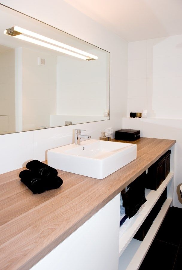 V nábytkové sestavě koupelny je integrovaná pračka, která je ukrytá za dvířky. Na laminátové desce v dekoru šedá bříza je posazeno umyvadlo. Podlahu tvoří lapovaná velkoformátová dlažba typ Cementi Negro a obklad Silk white matte. 