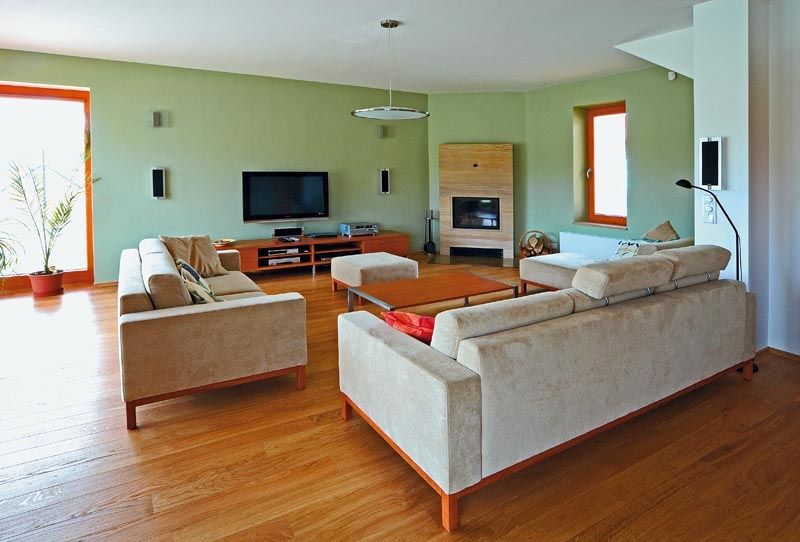 V obývacím pokoji majitelé domu citlivě sladili dubovou plovoucí podlahu se zelenkavým nátěrem stěn. Nábytek s mořenou dubovou dýhou si vybrali ve studiu BRIK. Pýchou rodiny je krb obložený velkoformátovými deskami z brazilského pískovce. 