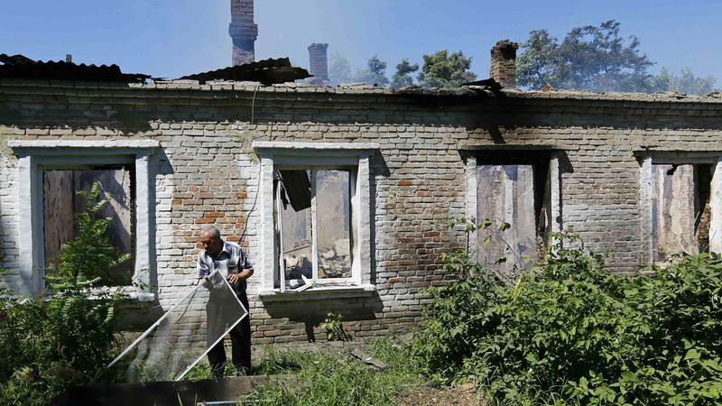 Obyvatel Slavjansku u domu poškozeného palbou 