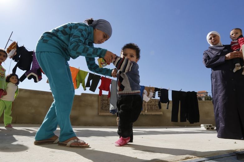 Syrská dívka pomáhá svému bratrovi, který může být nakažen obrnou, jít do mešity v Libanonu 