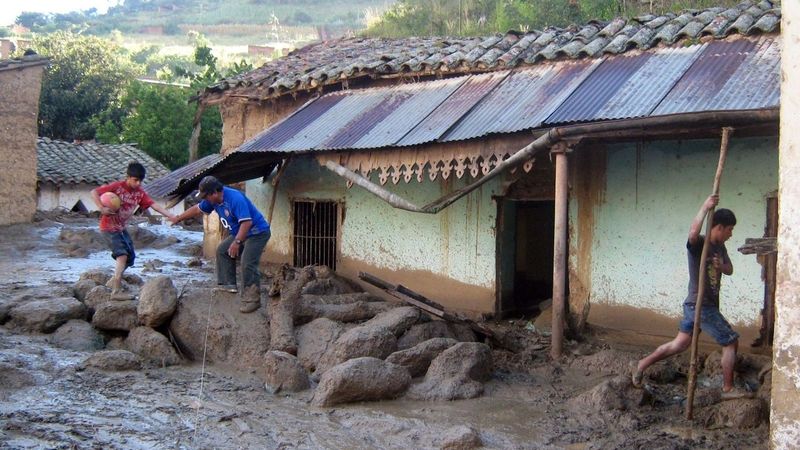 Peruánci přeskakují z kamene na kámen u domu, který zavalilo bláto 