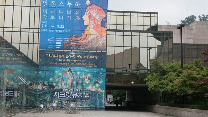 Plakát zvoucí na Muchovu výstavu na budově musea Hangaram 