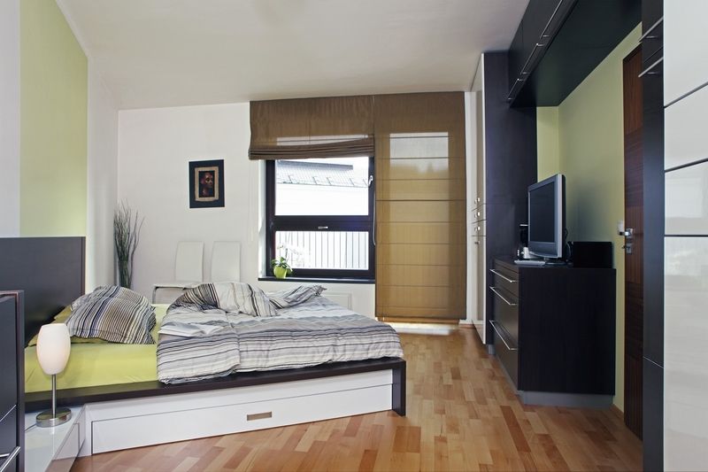 Zkosené stěny ložnice kopírují nejen skříně umístěné podél zdi, ale i postel, která má rovněž neobvyklý tvar. 