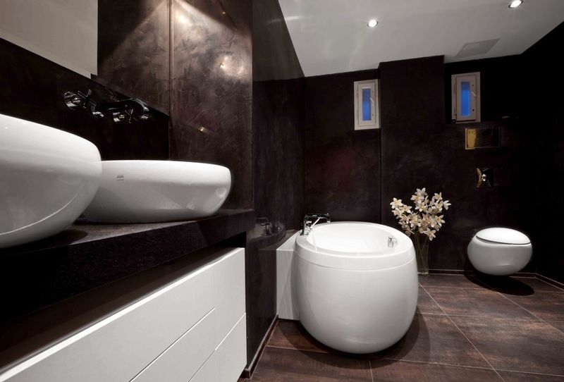 Stěny koupelny nejsou obloženy tradičními obkládačkami, ale upraveny benátským štukem v tuhově šedé a červené barvě. Na podlaze je slinutá dlažba s metalickým efektem čtvercového formátu o rozměru 60 x 60 cm. 