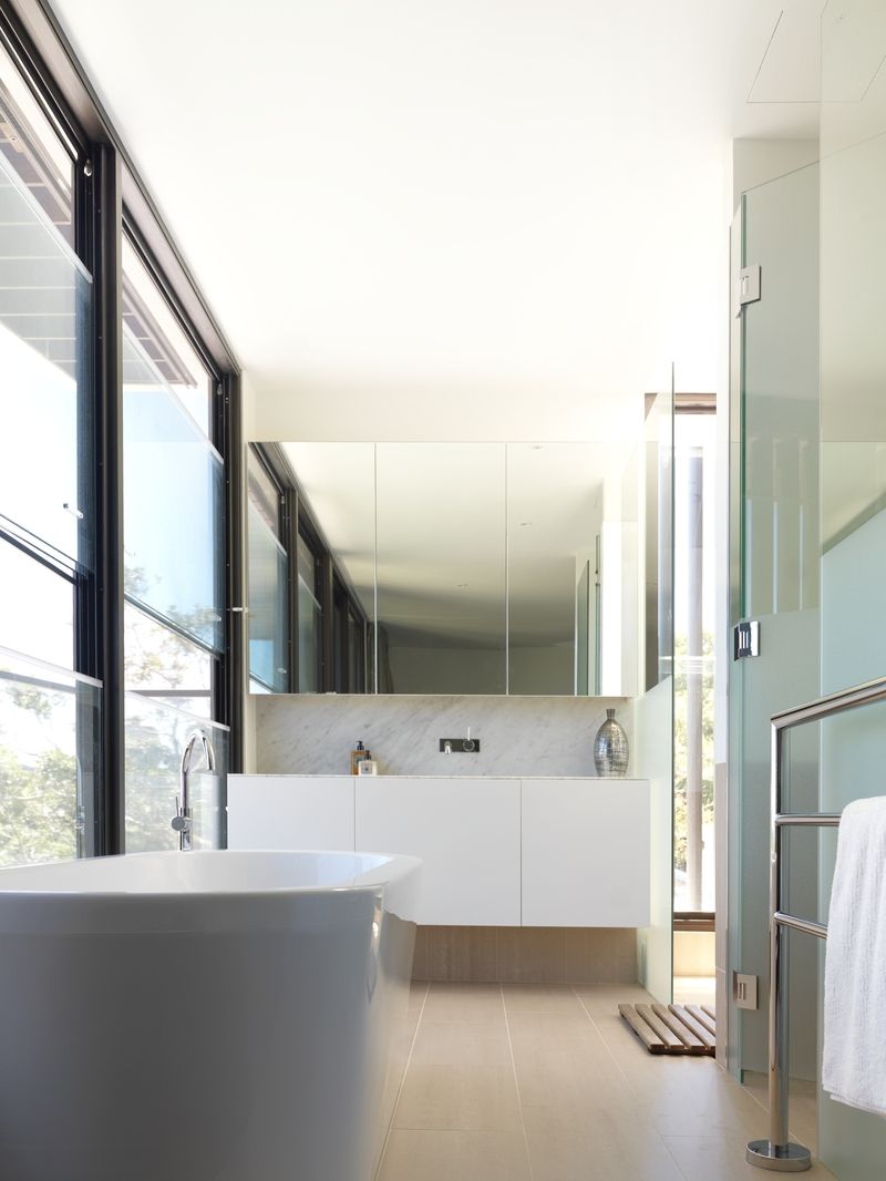 Nádherné výhledy nabízejí dokonce i velká okna v koupelně, které dominují sklo, kámen a kov.