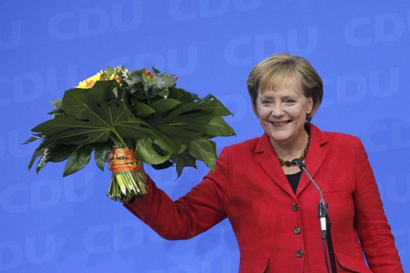 Angela Merkelová zdraví své stoupence se zdviženou kyticí na znamení vítězství, které potvrzují povolební odhady.