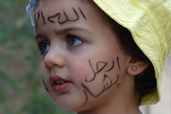 Děvčátko na demonstraci poblíž Damašku má na čele slogan 