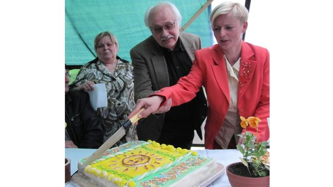 Vedoucí zahradnictví Miluška Pavlíková spolu s hercem Václavem Knopem slavnostně krájí dort s logem zahradnictví. 