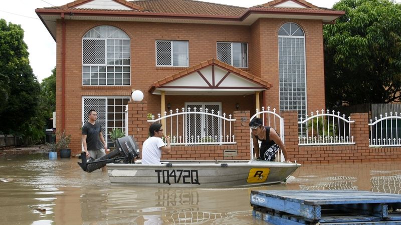Obyvatelé Brisbane plují kolem zaplaveného domu.
