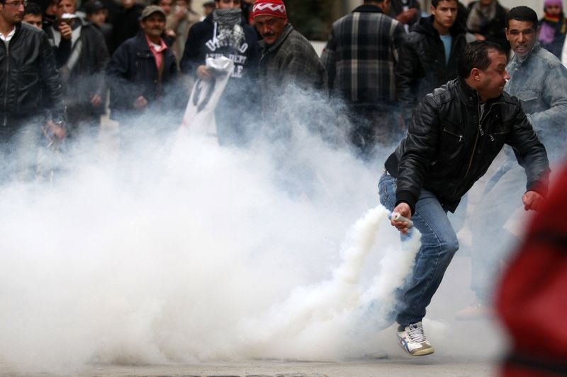 Tuniský demonstrant háže nádobu se slzným plynem zpět k policistům.