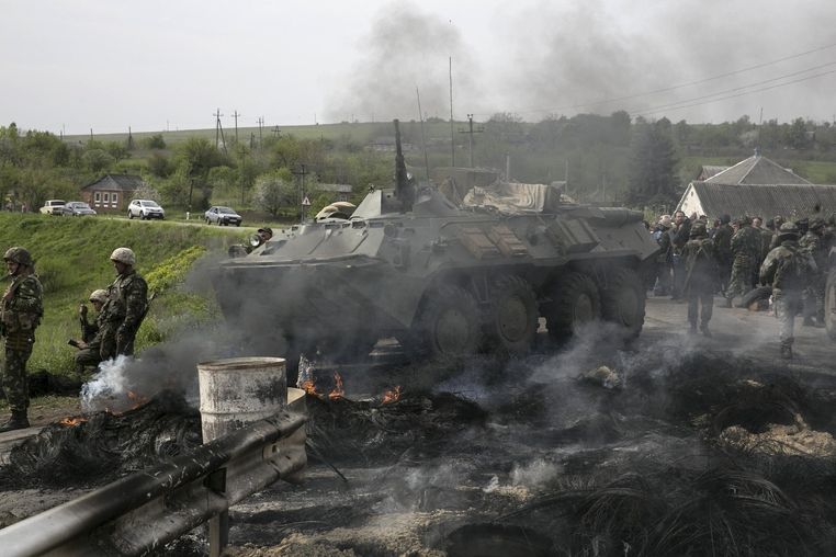 Ukrajinští vojáci střeží s transportérem dobyté kontrolní stanoviště