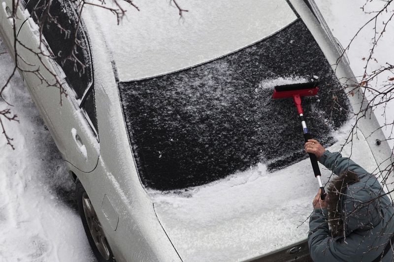 Moskvan odstraňuje led ze skla svého vozu.