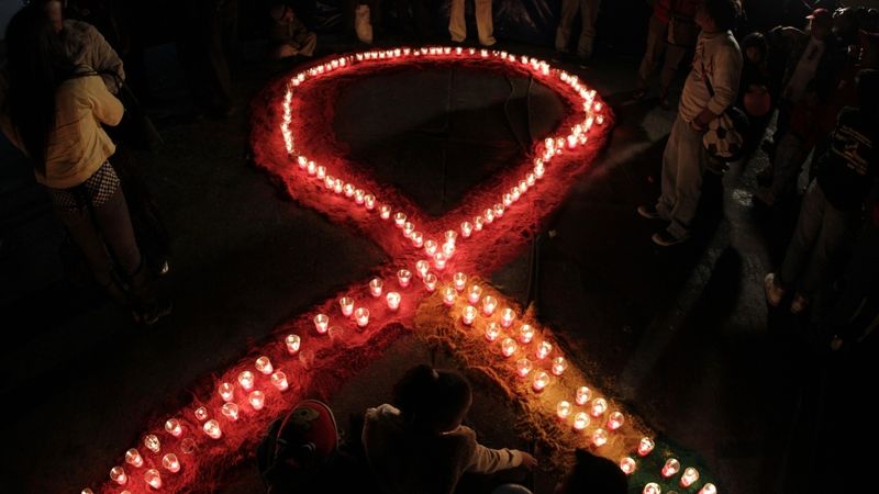 Symbol stužky pro nakažené AIDS vytvořený ze svíček 