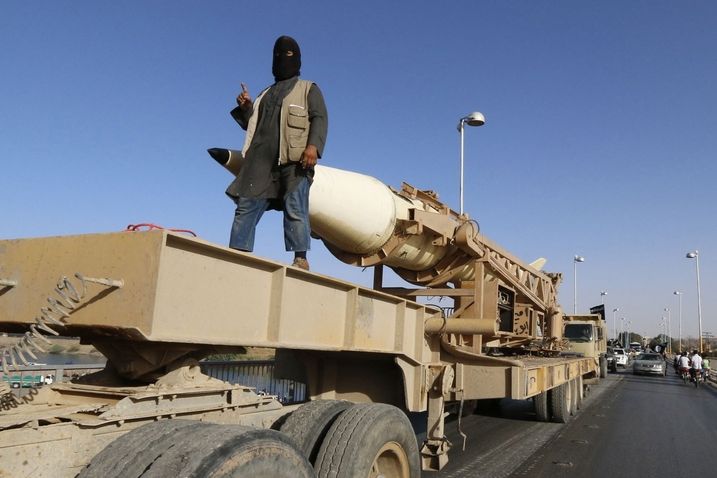 Bojovníci Islámského státu ukazují ukořistěnou techniku včetně raket. 
