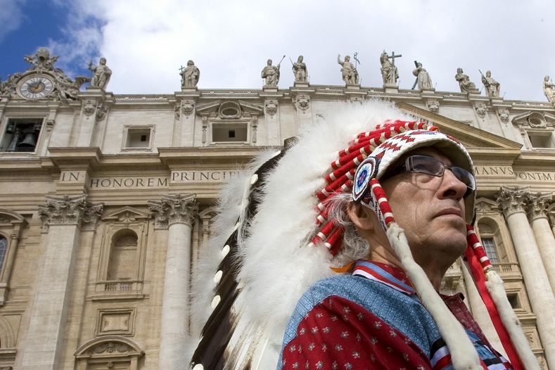 STŘEDA: Kanadský příslušník AFN (Seskupení prvotních národů) oblečen ve tradičním oděvu vítá papeže Benedicta XVI na Svatopetrském náměstí ve Vatikánu.