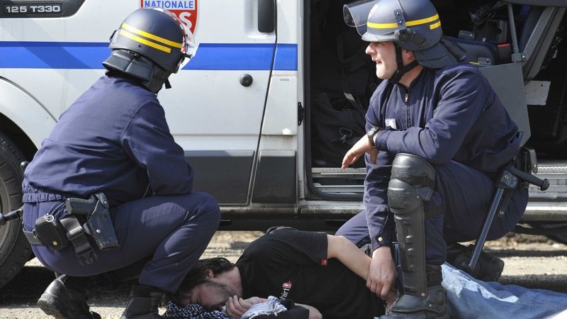 Francouzská policie u zadrženého demonstranta, který musí být ošetřen. 