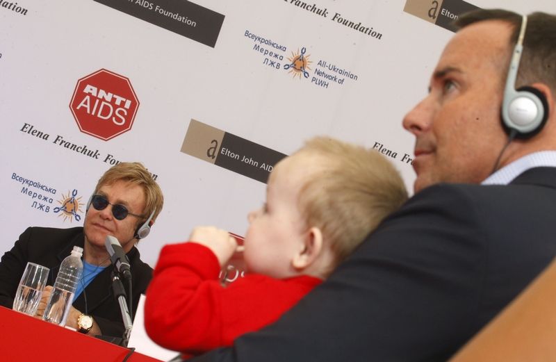 Elton John a jeho partner David Furnish, který drží malého ukrajinského chlapečka Lva.