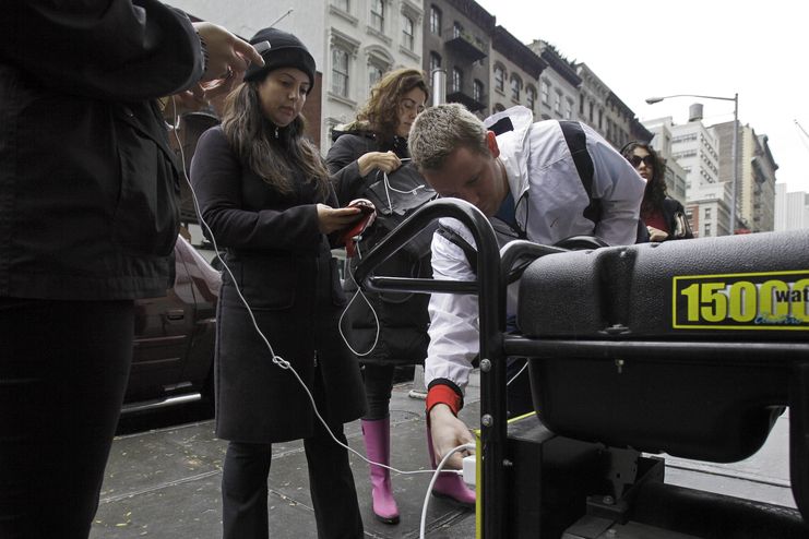 Lidé si dobíjejí telefony na ulici za drobný poplatek.