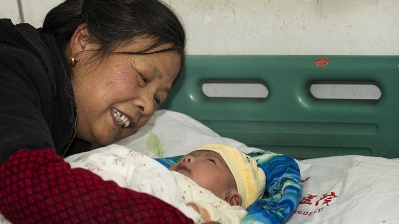 Čínská babička utěšuje vnouče zotavující se z prudké reakce po očkování.
