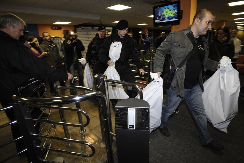 Policisté odnášejí z budovy pytle s dokumenty zabavenými v kanceláři redaktora České televize Karla Rožánka.