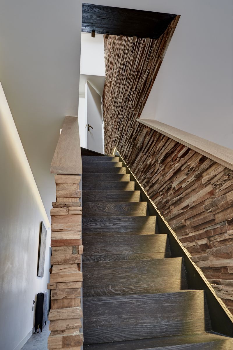 Stěny schodiště jsou obloženy kousky dřeva.