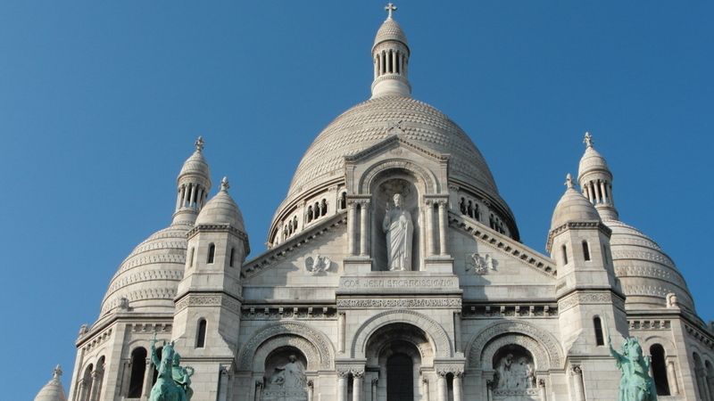 Sacre Coer, katedrála tyčící se nad Paříží na vršku Montmartre. Posaďte se na schody pod ní a kochejte se výhledem!