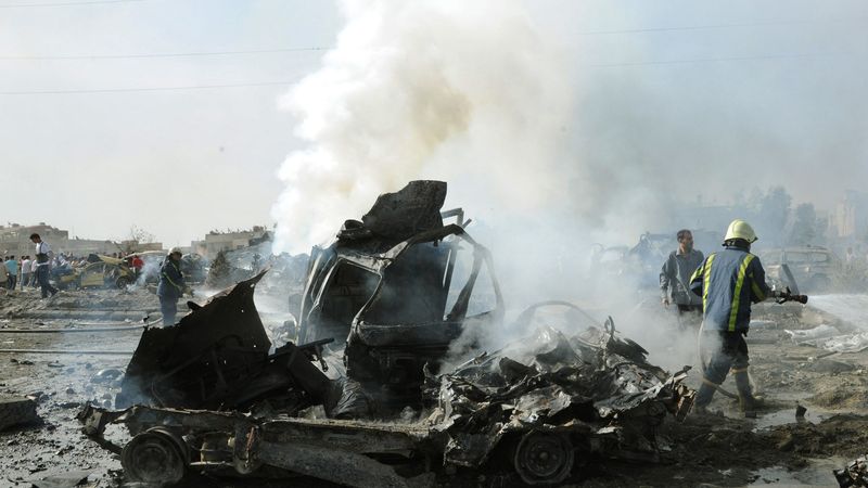 Syrští hasiči u vraku auta zničeného výbuchem ve čtvrtek