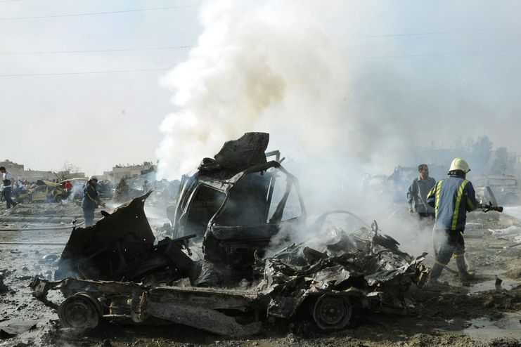 Syrští hasiči u vraku auta zničeného výbuchem