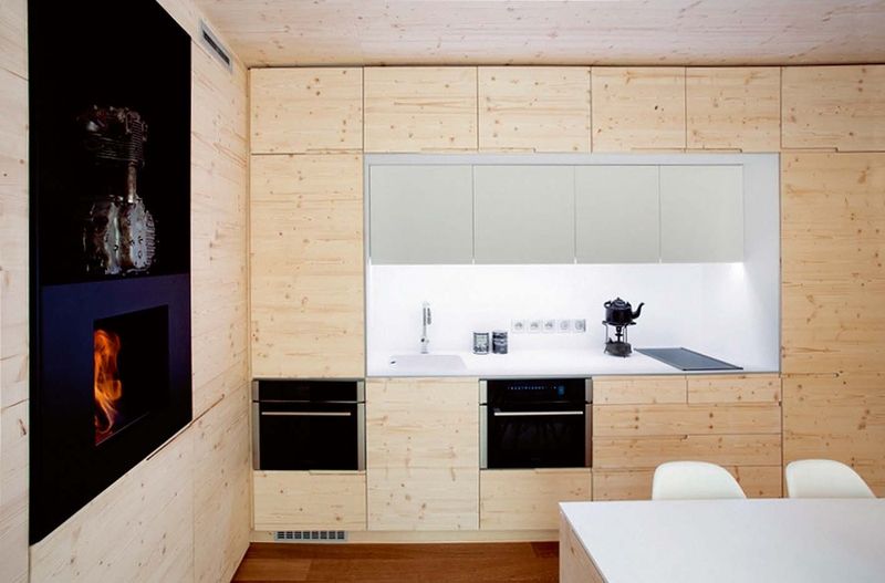 Kuchyňská linka v bělostné barvě má horní skříňky s podsvícením. Stěna nabízí velké množství úložných prostor. 
