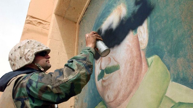 Seržant John Stanley vs. portrét Saddáma Husajna, předměstí Bagdádu v dubnu 2013.