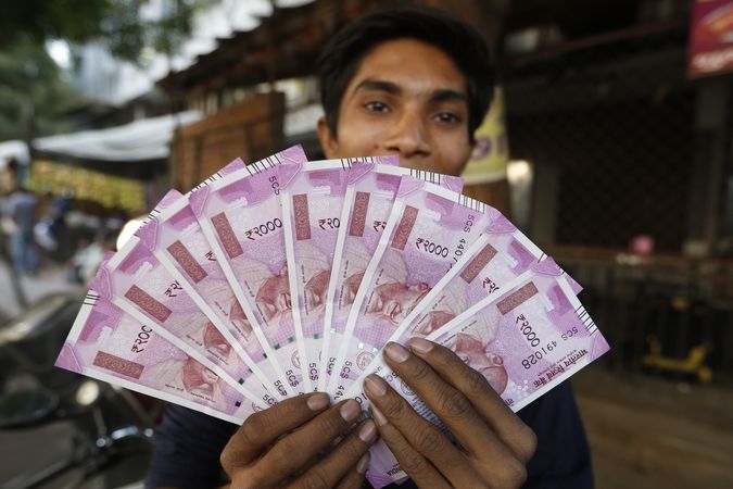 Indický mladík ukazuje 2000 indických rupií.