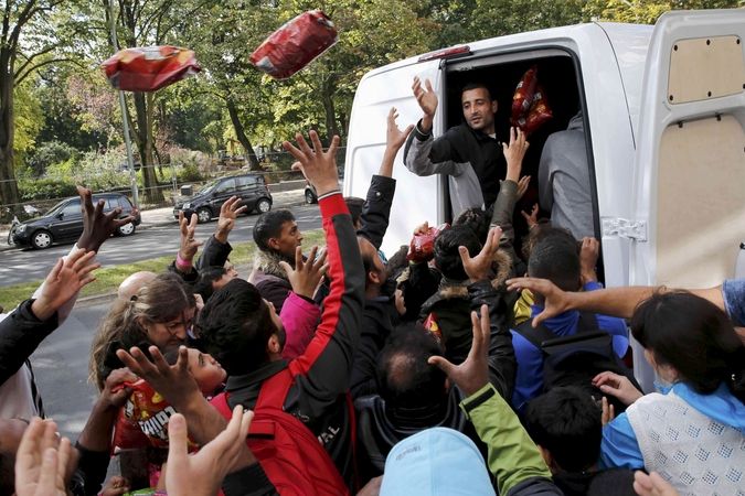 Němečtí dobrovolníci tureckého původu v Berlíně rozdávají jídlo a pití migrantům čekajícím na registraci. 