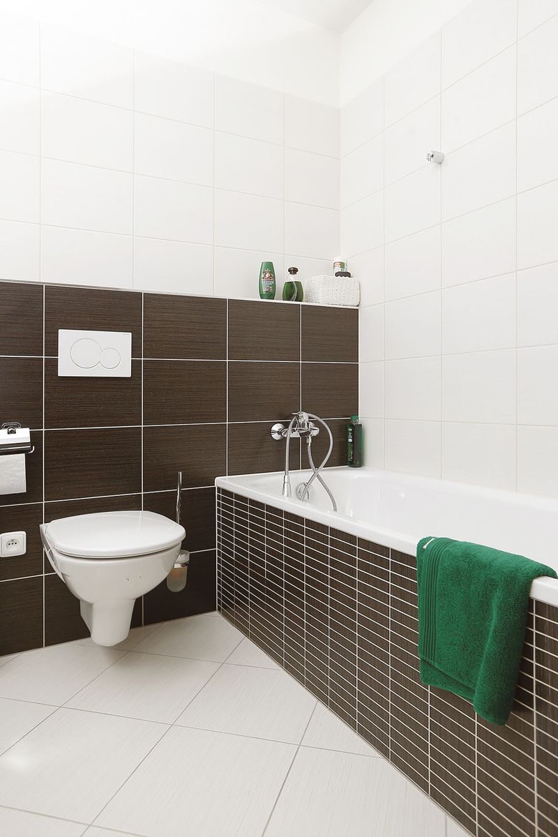 Prostorná koupelna s hnědými obklady v kontrastu s bílou sanitou zaujme na první pohled.