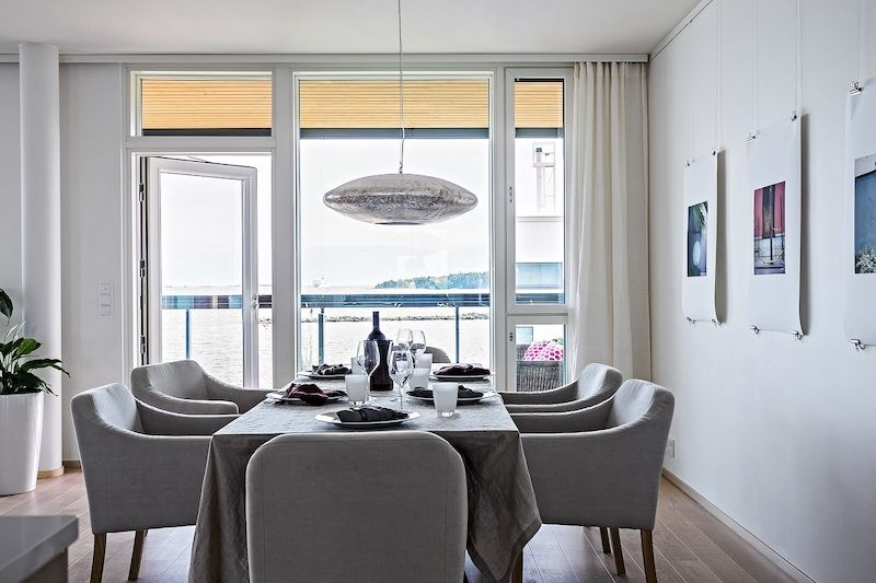 Větší jídelní stůl je doplněný židlemi Roma v příjemném šedém odstínu. Stěny zdobí na jemných drátech zavěšené fotky od Charlotty Boucht. 