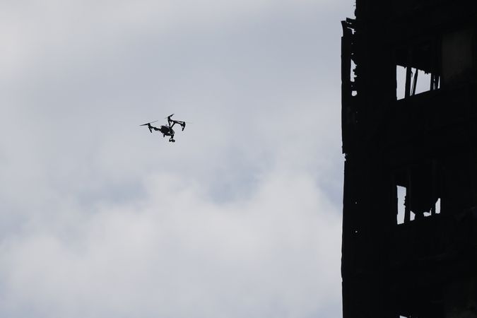 Dron letící na průzkum shořelého věžáku. 