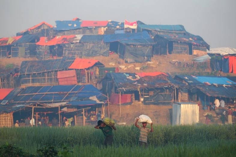 Uprchlíci z Barmy nesou pytle s pomocí do improvizovaného uprchlického tábora u Cox's Bazaru. 