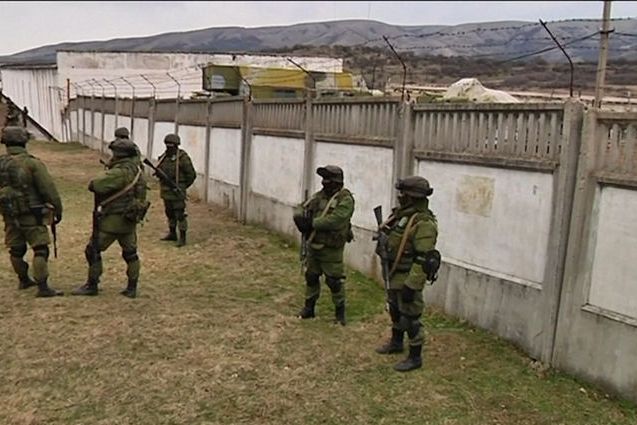 Ruští vojáci bez insignií na uniformách hlídkují u vojenské základny během krymské krize.