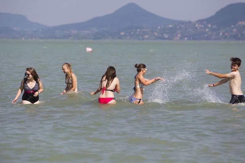 Mladí lidé se v horku osvěžují ve vodách Balatonu.