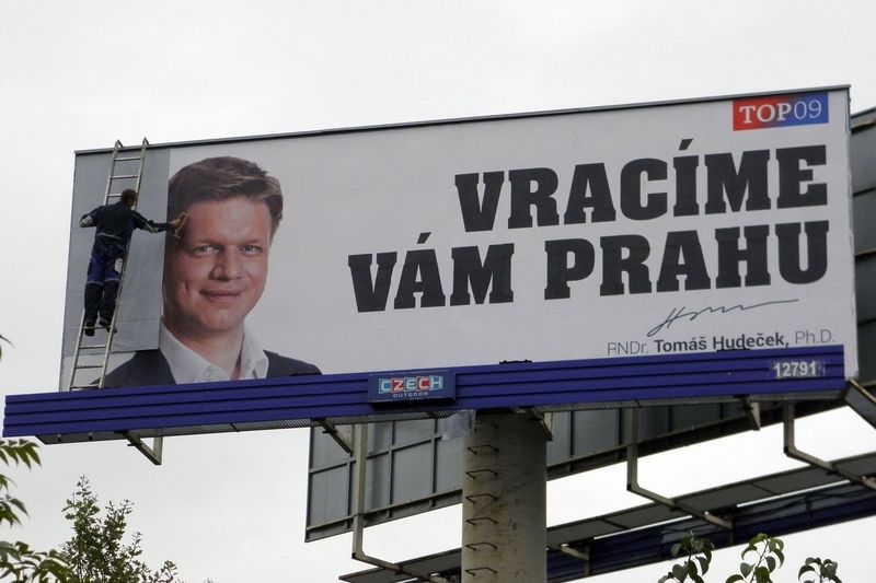 Pracovník firmy přelepuje billboard Tomáše Hudečka bílým papírem.