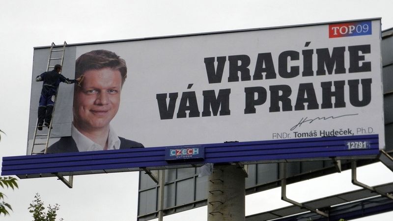 Pracovník firmy přelepuje billboard Tomáše Hudečka bílým papírem.