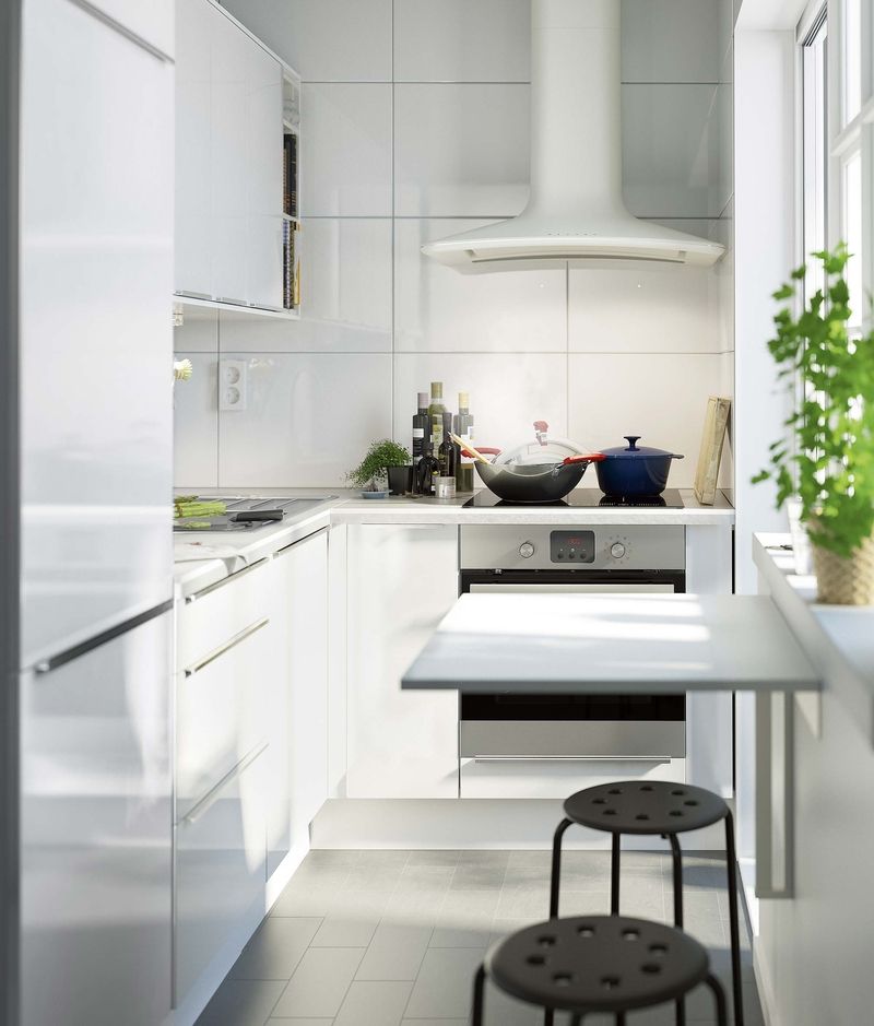 Kuchyně v úzkém prostoru ve tvaru písmene L. Nástěnný stolek lze kdykoli sklopit a tak uvolnit průchozí prostor. Stolek Norberg za 799 Kč. 