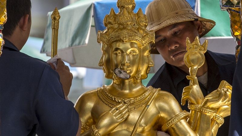 Muži čistí sochu u svatyně v centru Bangkoku, před kterou v pondělí explodovala bomba.