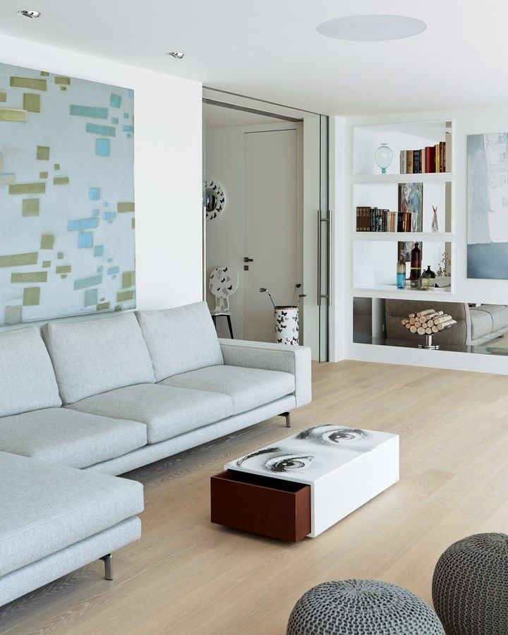 Obývací pokoj vymezuje stěna s nikami a lihovým krbem ze sádrokartonu. Vybavený je pohovkou Minotti a konferenčním stolkem Fornasetti s výsuvným úložným prostorem.