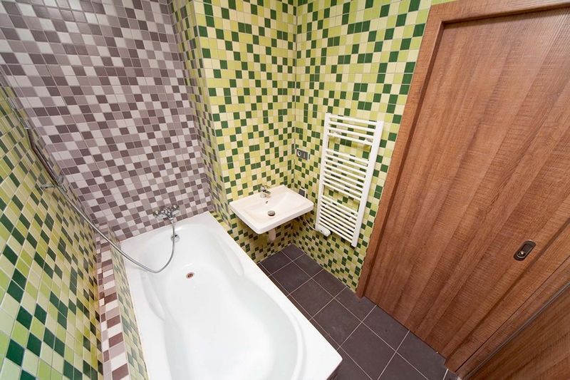 V koupelně se pokládaly obklady ze skleněné mozaiky v šedozelené kombinaci.