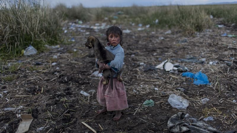 Dívka u jezera Titicaca pokrytého odpadky