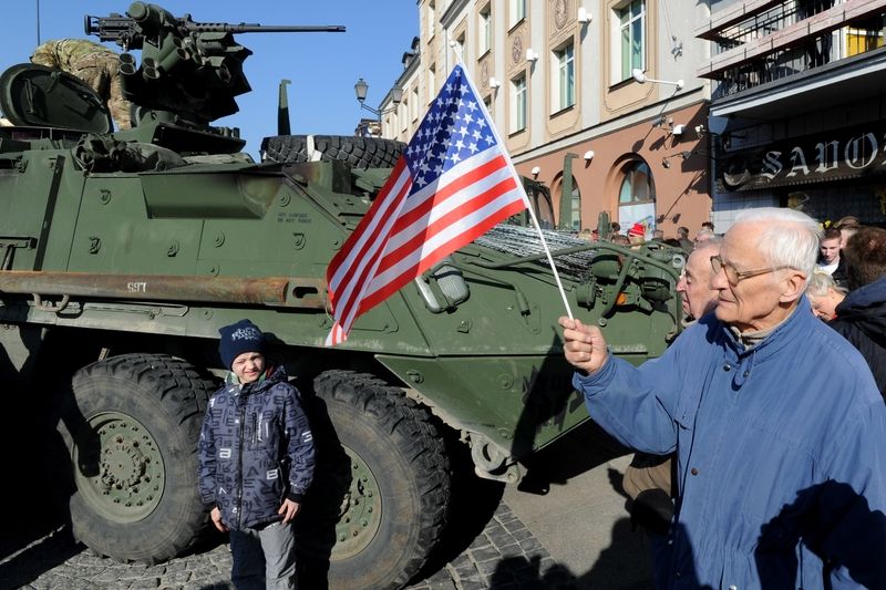 Muž s americkou vlajkou vítá armádu na náměstí v Bialystoku